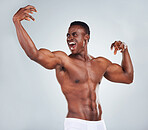 One excited African American fitness model posing topless in a underwear and looking muscular. Happy black male athlete isolated on grey copyspace in a studio wearing boxers