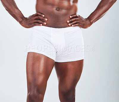Buy stock photo Closeup of one  African American fitness model posing in a underwear and looking muscular. Confident black male athlete isolated on grey copyspace in a studio wearing boxers with strong, toned legs
