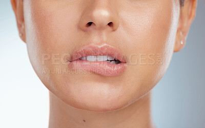 Closeup of seductive and sensual lip bite on unknown woman in studio. Caucasian model with sexy plump lips isolated against grey background and posing. Woman feeling flirty while biting her bottom lip