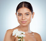 Portrait of beautiful woman holding white daisies while posing topless with copyspace. Caucasian model isolated against grey studio background with smooth skin, delicate healthy skincare routine