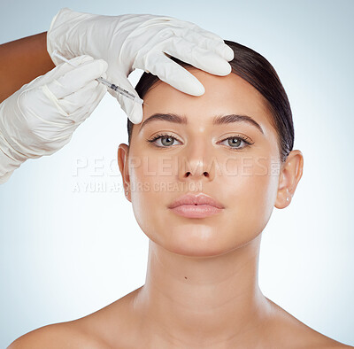 Closeup portrait of woman getting facial fillers or botox. Young caucasian model isolated against a grey studio background with copyspace. Dermatologist injecting patient during cosmetic procedure