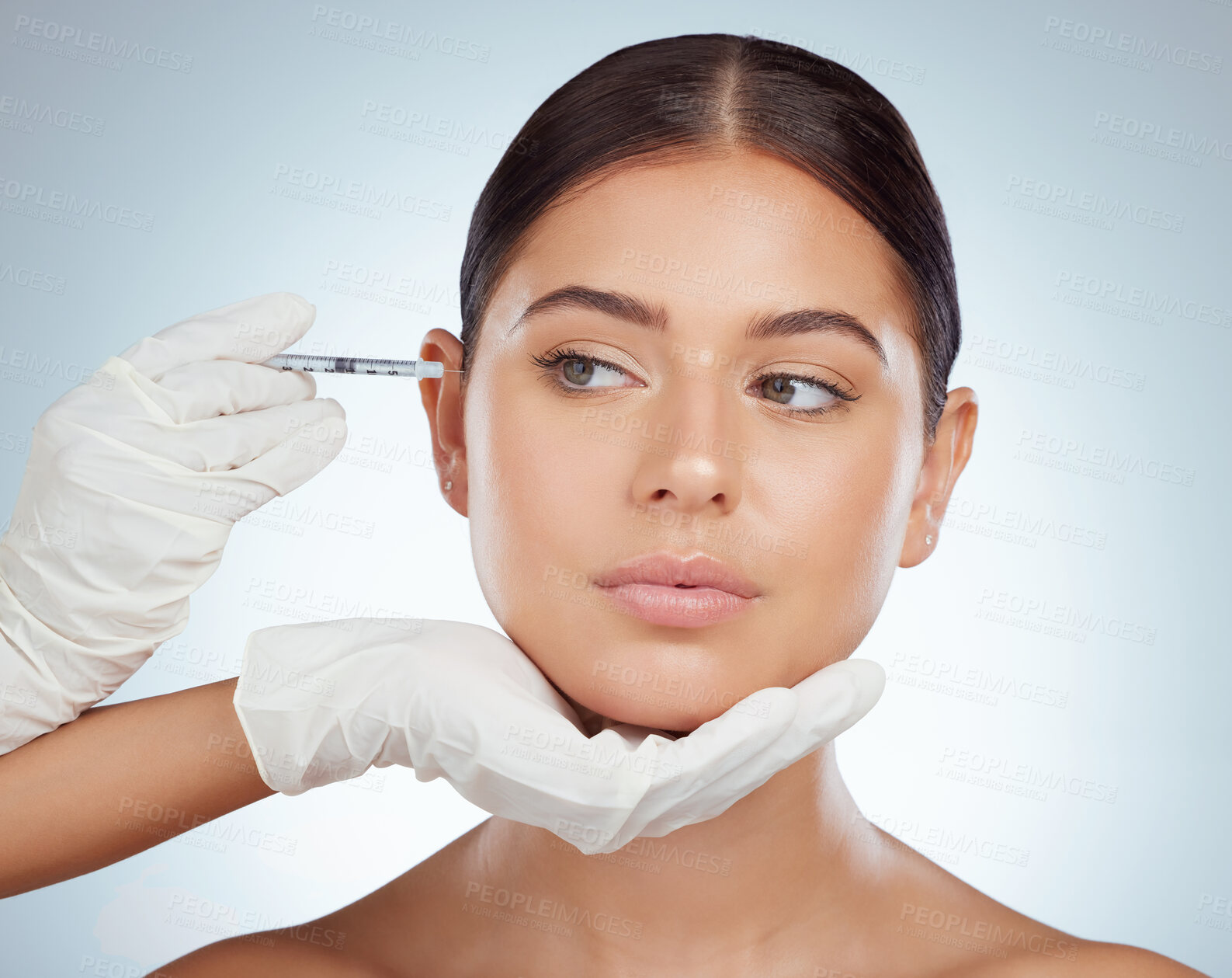 Buy stock photo Beautiful woman getting facial fillers or botox. Young caucasian model isolated against a grey studio background with copyspace. Dermatologist injecting patient during anti ageing cosmetic procedure
