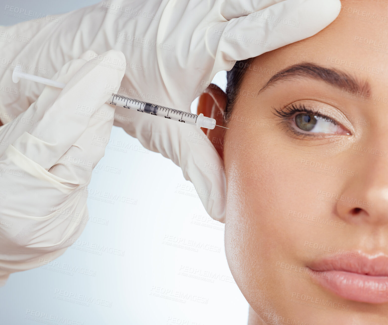 Buy stock photo Closeup of woman getting facial fillers or botox. Young caucasian model isolated against a grey studio background with copyspace. Dermatologist injecting patient during anti ageing cosmetic procedure