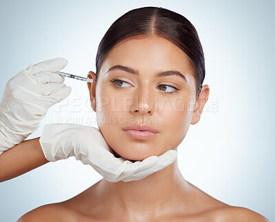 Beautiful woman getting facial fillers or botox. Young caucasian model isolated against a grey studio background with copyspace. Dermatologist injecting patient during anti ageing cosmetic procedure