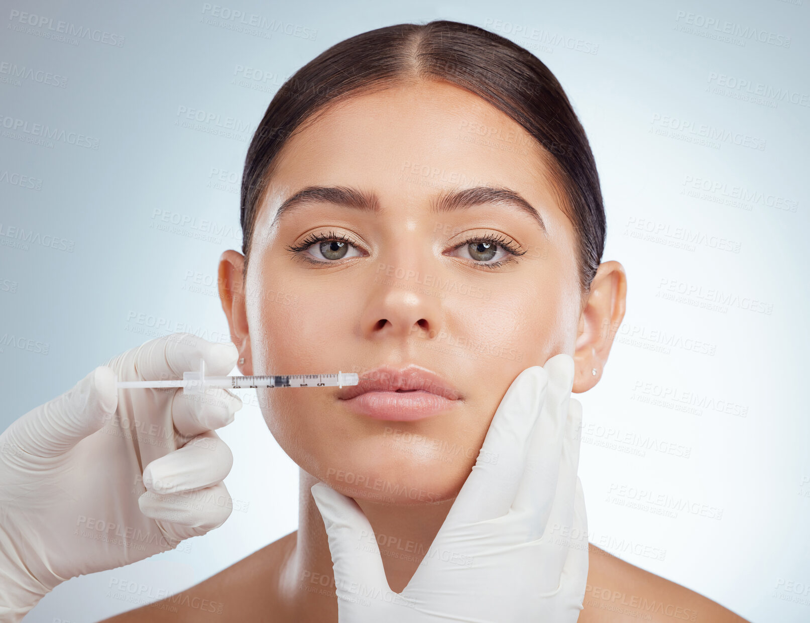 Buy stock photo Closeup portrait of woman getting lip fillers or botox. Young caucasian model isolated against grey studio background with copyspace. Dermatologist injecting patient in anti ageing cosmetic procedure