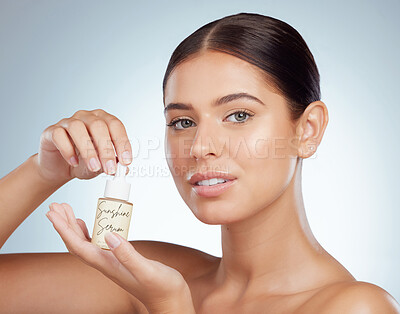 Portrait of beautiful woman holding face serum while posing with copyspace. Young caucasian model isolated against grey studio background. Using skin oil for healthy glowing skin for skincare routine