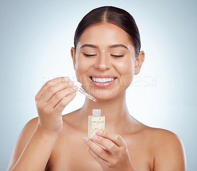 Buy stock photo Smiling beautiful woman using dropper and getting ready to apply face serum. Happy caucasian model isolated against grey studio background with copyspace using skin oil for healthy glowing skincare