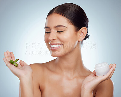 Buy stock photo Smiling beautiful woman holding aloe vera leaf for her skincare routine. Caucasian model isolated against grey studio background and posing with copyspace. Organic plants for hydration and moisture