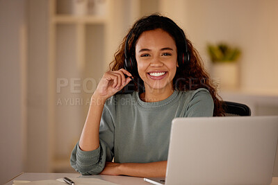 One young woman using headset and working late on a laptop in an office. Happy woman doing freelance work as a call centre agent. Consultant operating a helpdesk for customer care, sales and support
