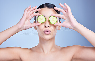 Buy stock photo A beautiful mixed race woman holding cucumber slice. Hispanic model using cucumber sooth her eyes against a blue copyspace background