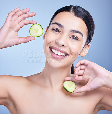 Buy stock photo Studio Portrait of a beautiful mixed race woman holding cucumber slice. Hispanic model promoting the skin benefits of a healthy diet against a blue copyspace background
