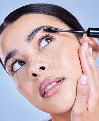Closeup of a beautiful young mixed race woman with glowing skin posing against blue copyspace background. Hispanic woman with natural looking eyelash extensions applying mascara