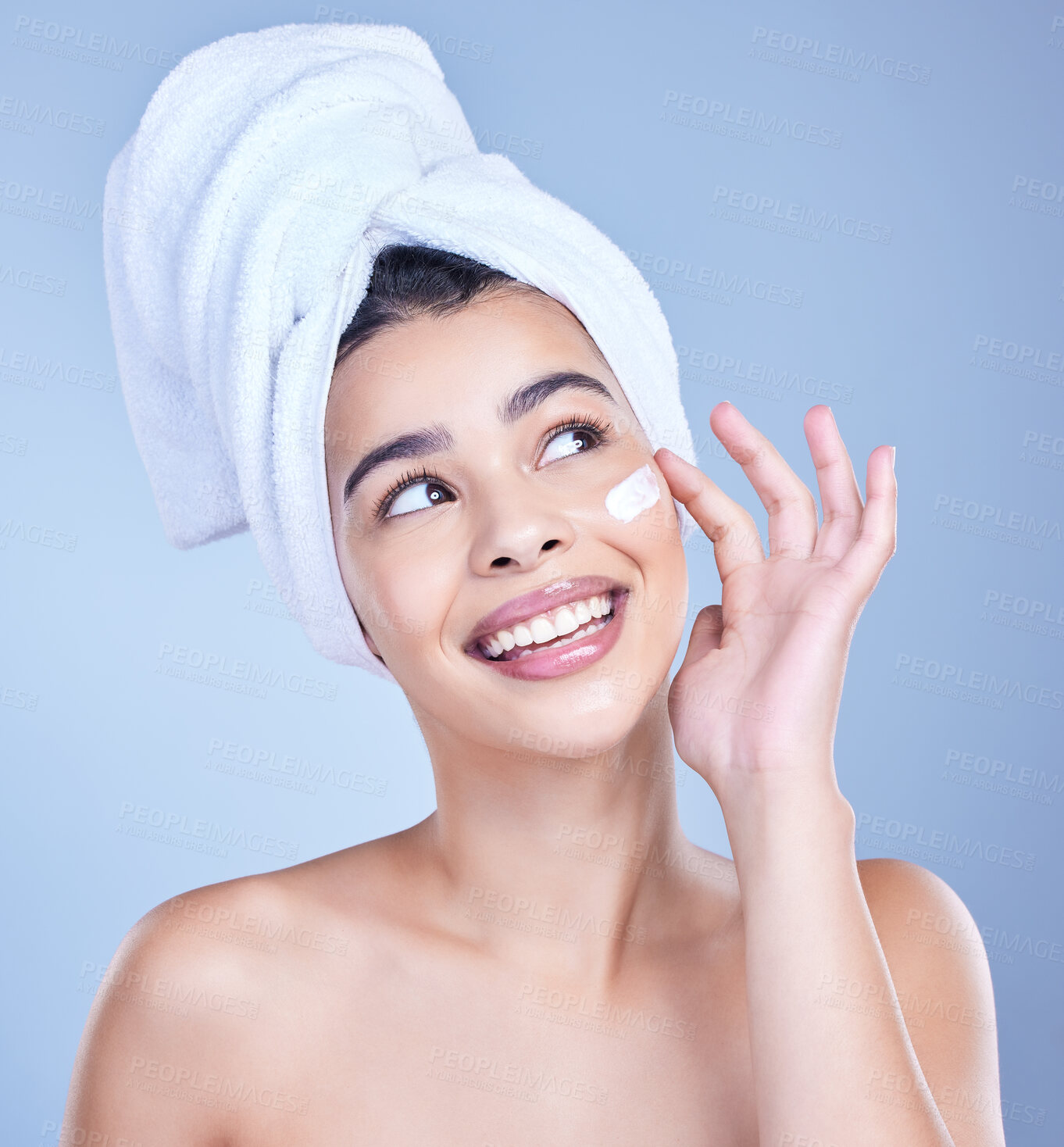 Buy stock photo A beautiful smiling happy mixed race woman applying cream to her face. Hispanic model with glowing skin against a blue copyspace background