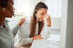 Stressed young hispanic call centre agent looking worried and suffering with headache while being comforted and consoled by a colleague in an office. Woman offering sympathy and support to frustrated and upset coworker