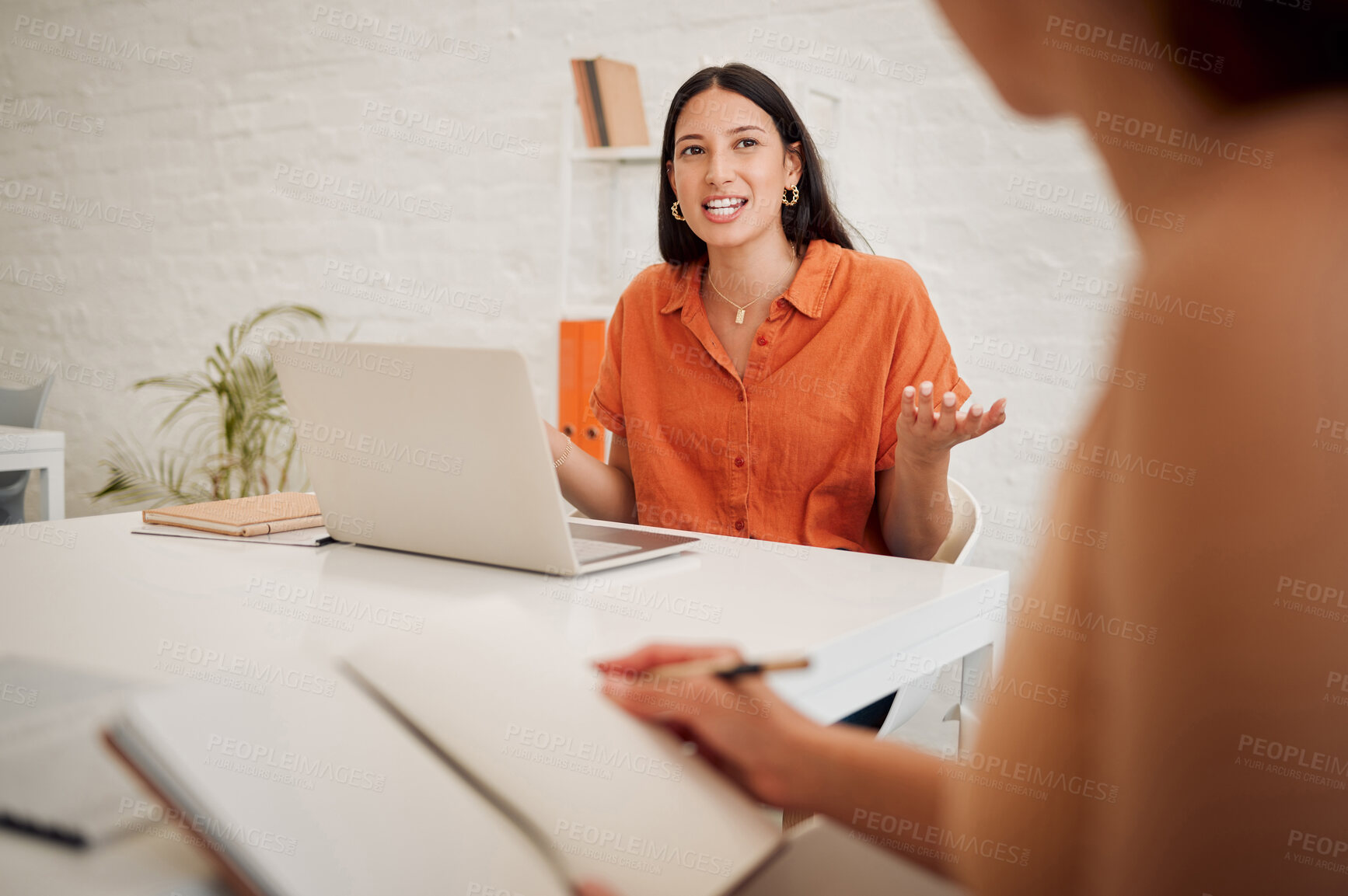 Buy stock photo Young hispanic business woman using a laptop while speaking to colleagues during a meeting in an office boardroom. Staff sharing feedback and explaining ideas while brainstorming in a creative startup agency
