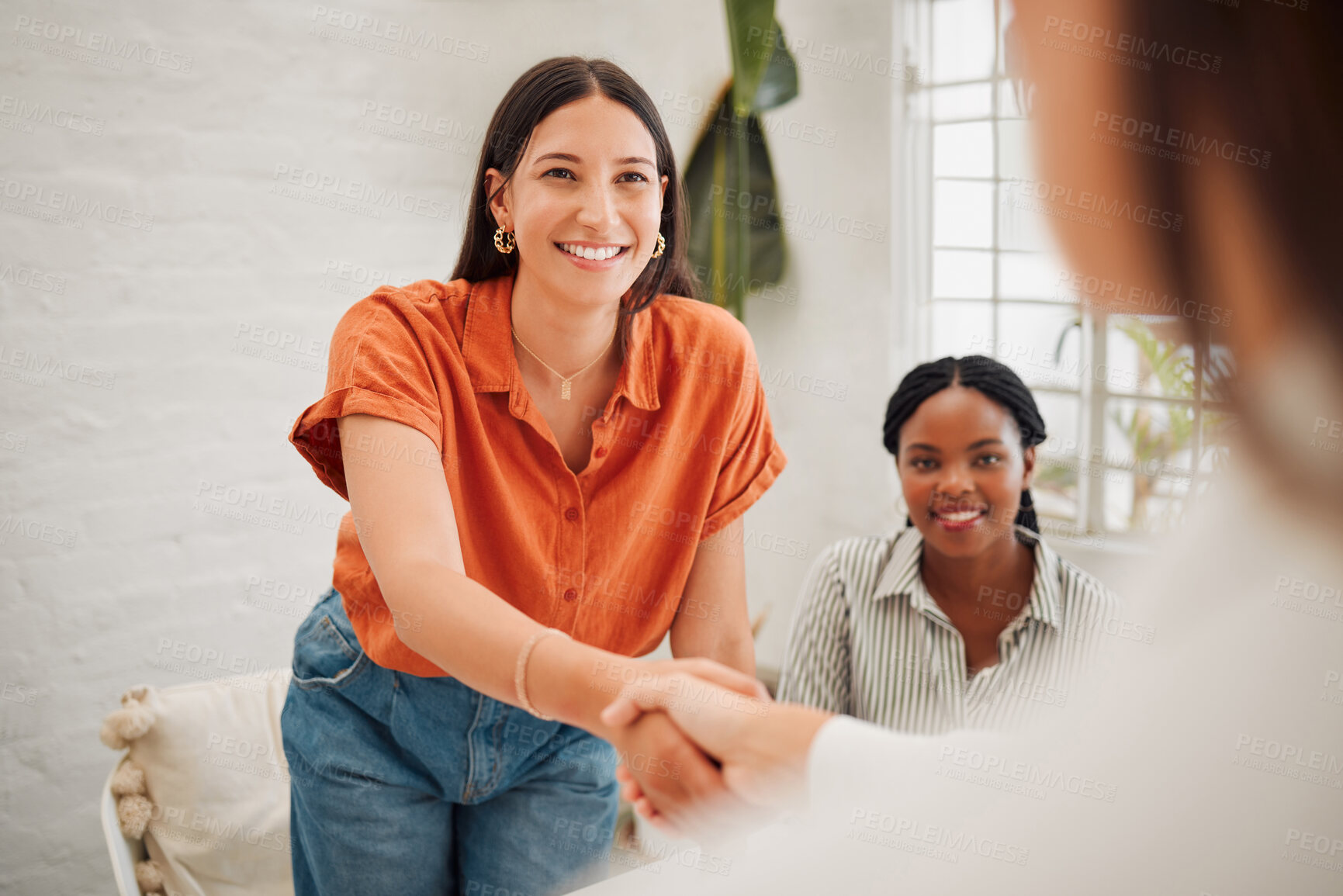 Buy stock photo Confident young hispanic businesswoman shaking hands with colleague during a meeting in an office. Motivated woman looking happy after receiving a successful promotion, deal and merger. Coworkers greeting while collaborating in a creative startup agency