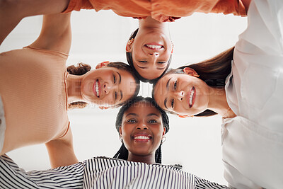 Buy stock photo Portrait of happy businesswomen joining their heads together in a circle in an office at work. Diverse group of cheerful businesspeople having fun standing with their heads together in support