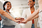 Group of happy businesswomen stacking their hands together in an office at work. Diverse group of businesspeople having fun standing with their hands stacked support