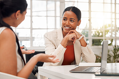 Buy stock photo Two young happy mixed race businesswomen having a meeting in a boardroom at work. Cheerful businesspeople talking while planning together in an office