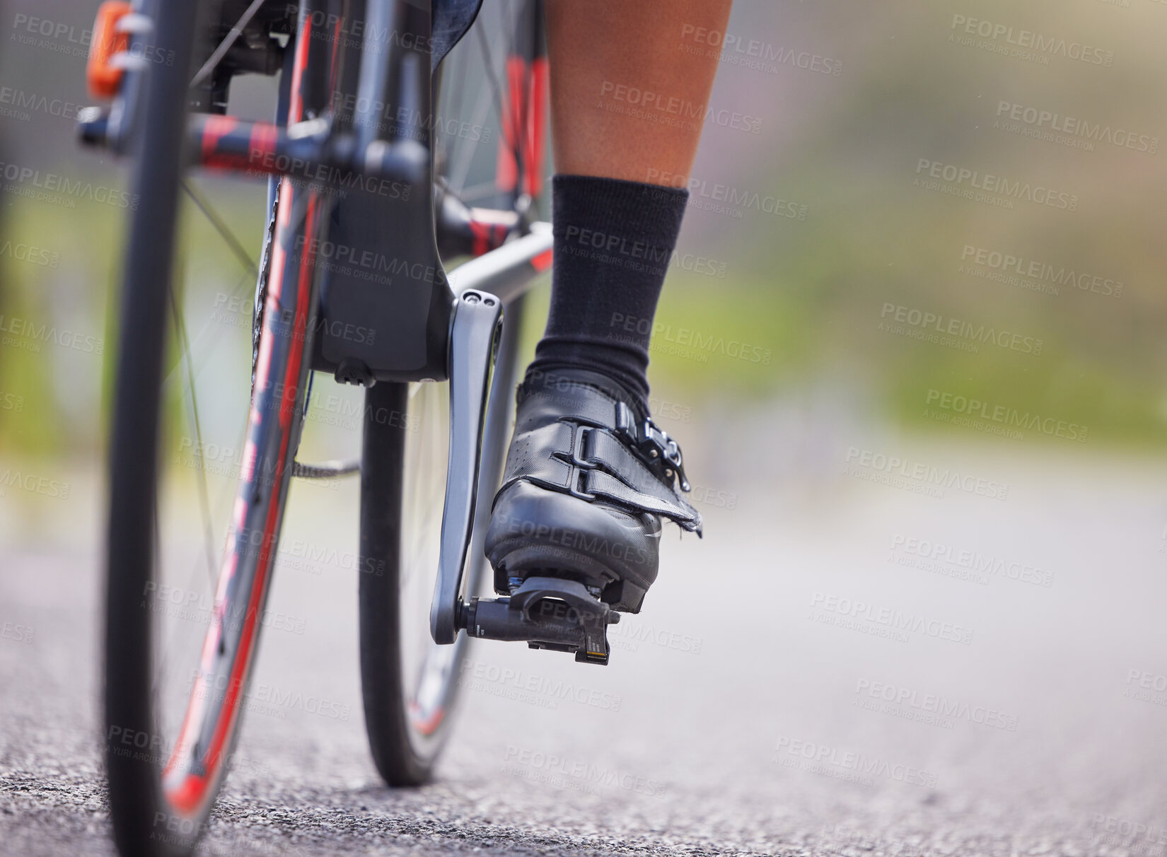 Buy stock photo Closeup of the feet of one young woman exercising outside in the forest. Healthy and sporty female athlete with her feet on pedals out for a cycle. Endurance and cardio during a workout in the woods