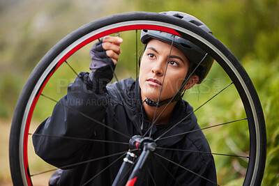 Buy stock photo One athletic young woman fixing the wheel of a bike while cycling outdoors. Sporty female wearing helmet and checking the air pressure of a bicycle tyre for repairs while riding outside for exercise 