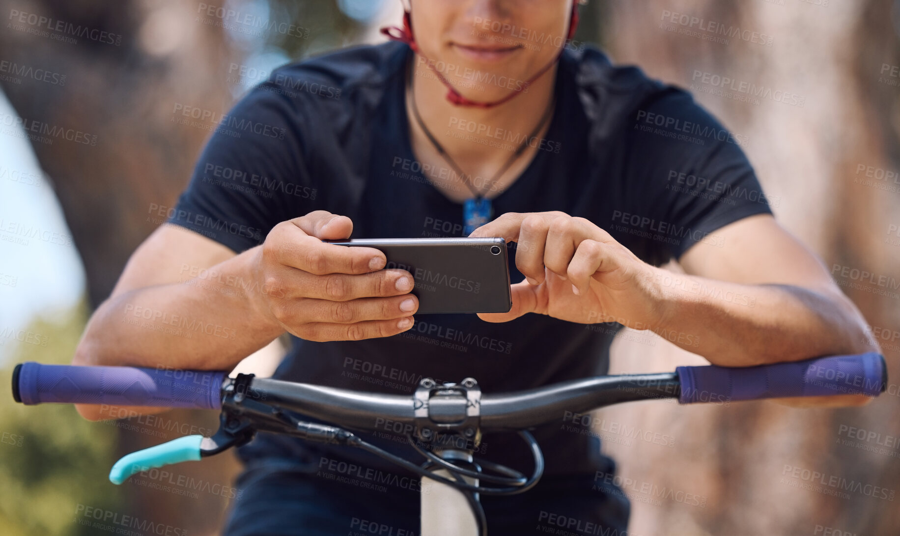 Buy stock photo One athletic unrecognizable male using a cellphone while cycling outside on a bike for exercise. Sporty fit male taking a break to text, browse online and use navigation apps while standing outside