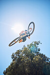 Man showing his cycling skills while out cycling outside. Adrenaline junkie practicing a dirt jump. Male wearing a helmet doing tricks with a bike. Portrait while doing extreme sports with a bicycle