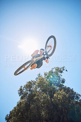 Man showing his cycling skills while out cycling outside. Adrenaline junkie practicing a dirt jump. Male wearing a helmet doing tricks with a bike. Portrait while doing extreme sports with a bicycle
