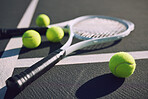 Tennis racket and balls on an empty sports court outside on a sunny day. Sports gear and equipment for leisure or a professional player. A hobby that promotes exercise, fitness and wellness