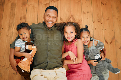 A happy mixed race family of four relaxing and lying on the lounge floor together. Loving black single parent bonding with his kids while being affectionate at home