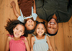 A happy mixed race family of four relaxing and lying on the lounge floor together. Loving black single parent bonding with his kids while being affectionate at home