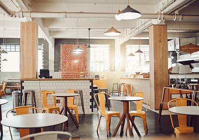 Interior of empty modern cafe or restaurant during the day. Round tables and yellow chairs in a rustic cafe. Open space coffee shop with exposed pipes and pendant hanging lights