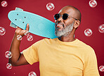 One mature african american man standing with a mini skateboard surround by many bubbles in studio isolated against a red background. Handsome and carefree man wearing sunglasses and smiling happily