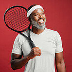 One happy mature african american man standing against a red background in studio and posing with a tennis racquet. Smiling black man feeling fit and sporty while playing a match. Ready for the court