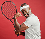 One happy mature african american man standing against a red background in studio, flexing his bicep while posing with a tennis racquet. Smiling black man feeling fit and sporty while playing a match
