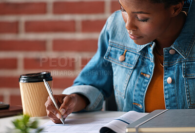 A focused young woman signing financial documents for her home insurance. A young woman signing a loan application at the bank to pay her bills. A woman reading and signing paperwork for an investment