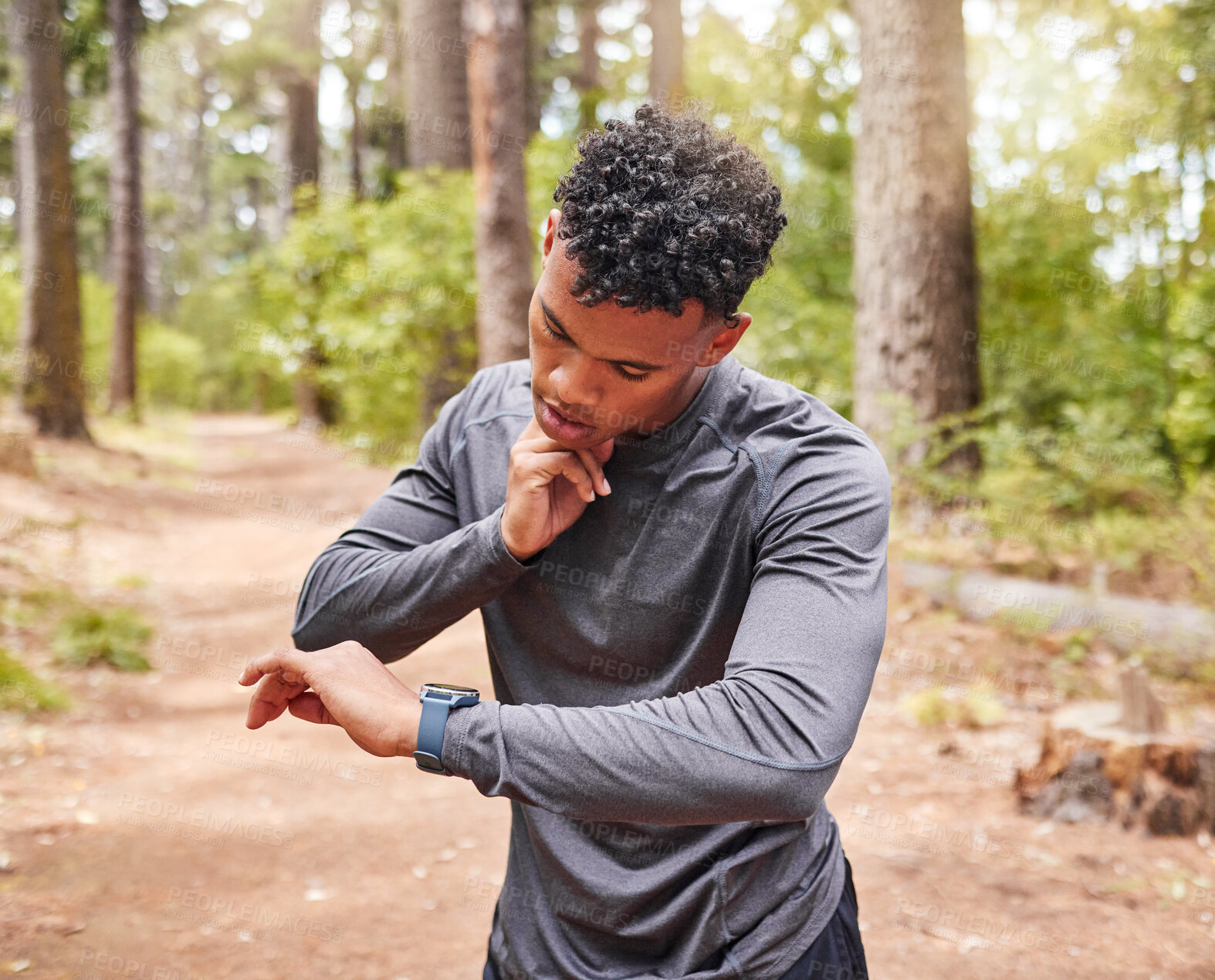 Buy stock photo African American man checking his pulse while wearing a smartwatch and tracking his pulse, heartbeat and cardio health. Athlete using a device to keep track of his vitals while out jogging in a park 
