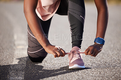 Buy stock photo Active and fit woman tying the laces of her sneakers for exercise outdoors. Athlete fastening her shoes to get ready for a run or jog in the morning. Preparing for a refreshing cardio workout outside