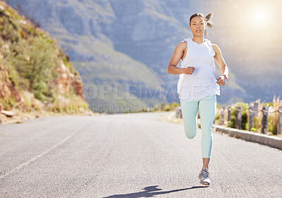Young mixed race hispanic female athlete running outside in nature on the road. Exercise is good for your health and wellbeing. Running in the morning. Enjoying, relaxing, positive