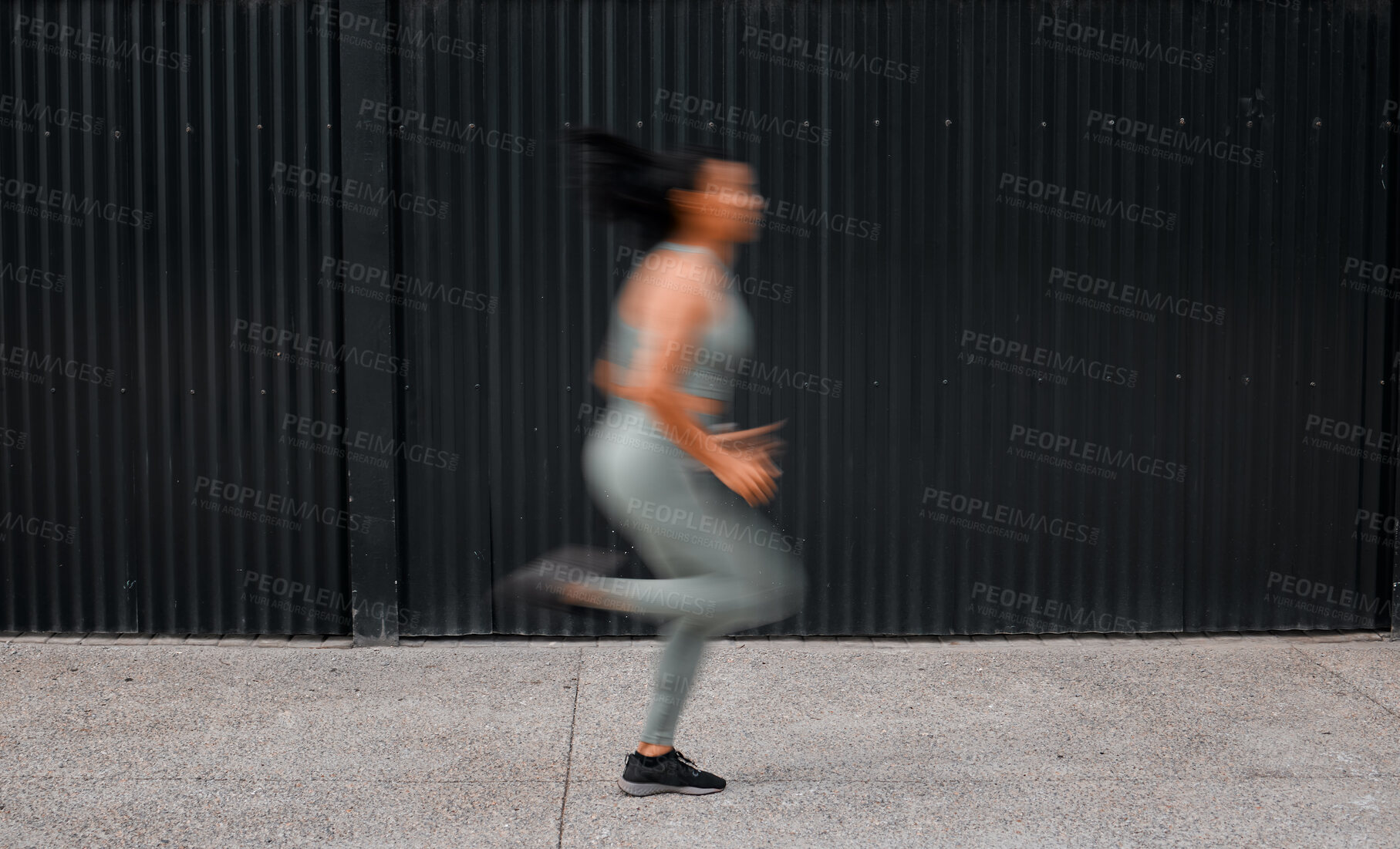 Buy stock photo Dedicated young african american sportswoman running outside in blurred motion through the city. Athletic mixed race woman working out, focusing on cardio and endurance while jogging outside