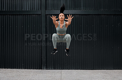 Buy stock photo Full body fit and active mixed race woman jumping while working out alone outside. Focused and toned athlete doing cross fit and exercising downtown in a city. Physical activity and sports are healthy