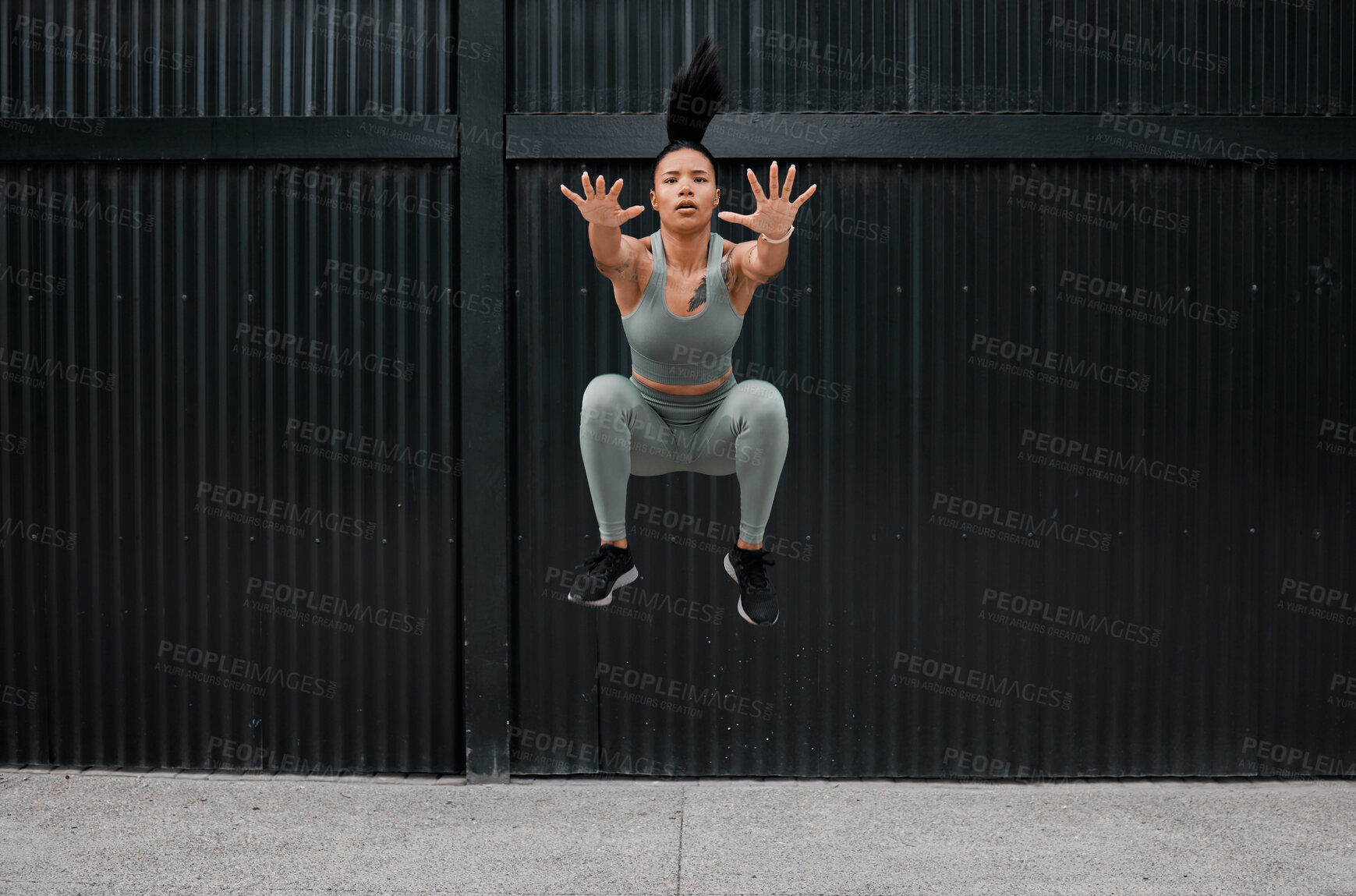 Buy stock photo Full body fit and active mixed race woman jumping while working out alone outside. Focused and toned athlete doing cross fit and exercising downtown in a city. Physical activity and sports are healthy
