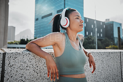 Buy stock photo Young mixed race hispanic female athlete wearing headphones and listening to music while standing outside in the city. Positive, happy, workout. Taking a break