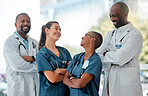 Group of happy doctors and nurses standing in a line with their arms crossed while working at a hospital. Cheerful expert medical professionals laughing at work together at a clinic