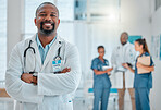 Mature african american male doctor standing with his arms crossed while working at a hospital. One expert medical professional smiling while standing at work at a clinic
