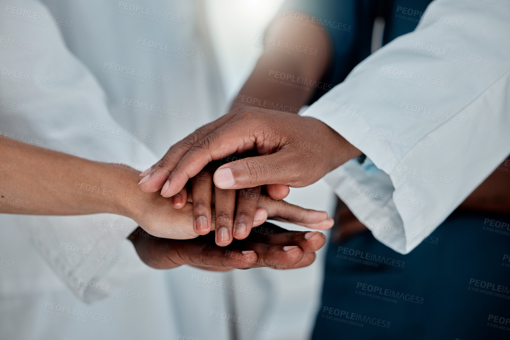 Buy stock photo Group of doctors stacking their hands together in support while working at a hospital. Medical professionals joining their hands in unity and motivation while working at a clinic
