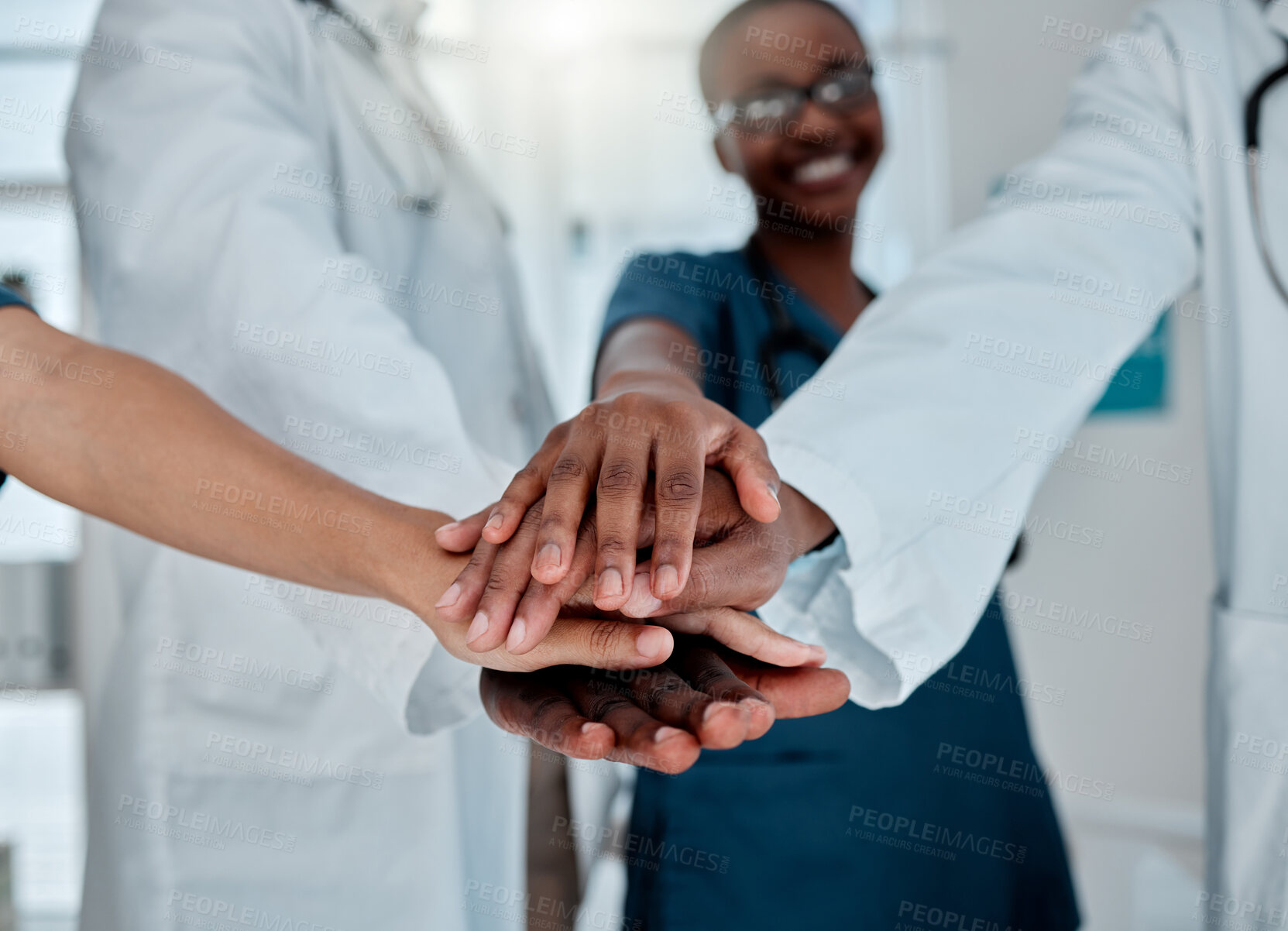 Buy stock photo Group of diverse doctors stacking their hands together in support while working at a hospital. Medical professionals joining their hands in unity and motivation while working at a clinic