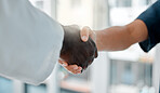 Two doctors shaking hands while working together at a hospital. Medical professionals greeting each other while at work at a clinic. Colleagues showing support to each other
