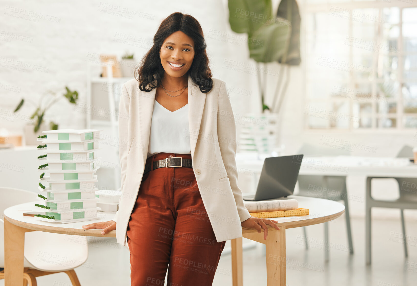 Buy stock photo African american businesswoman leaning on her desk. Portrait of a young businesswoman in her office. Creative designer working in her agency. Powerful businesswoman standing in her architecture agency