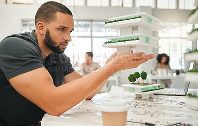 Buy stock photo Young architect looking at 3D model. Professional architect planning a building project. Focused designer holding a building model. Corporate creative working in his office.